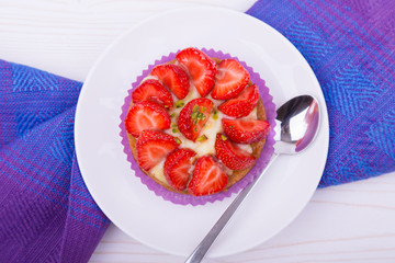 cake with strawberries and custard on a white plate with a spoon. on colored napkin. top view. Portion baking, linen napkins