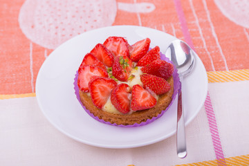 cake with strawberries and custard on a white plate with a spoon. on colored napkin. top view. Portion baking, linen napkins