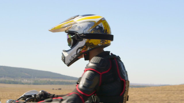 Enduro racer in motorcycle protective gear riding dirt bike vehicle shot side view closeup 