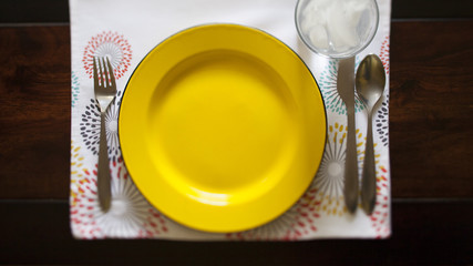 full place setting with yellow plate on patterned place mat