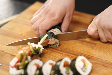 Sushi master kroi nożem rolki sushi