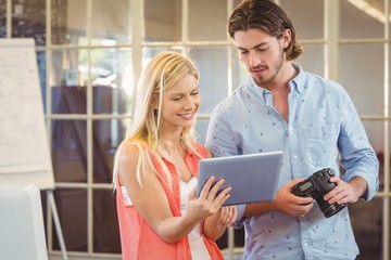 Businesswoman showing something to male colleague on tablet