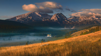 Idyllic mountain panorama at misty sunrise