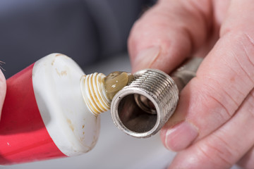 Plumber putting sealing paste on a thread