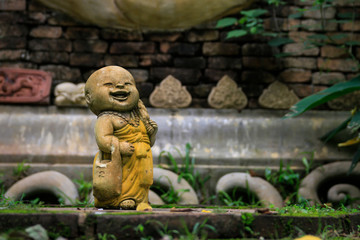 Buddhist novice holding alms bowl clay doll at Thai Buddhist temple