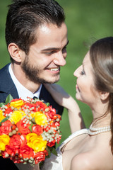 Happy just married bride and groom on green grass background