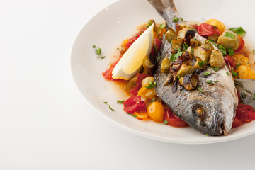 Fried dorado with vegetables and lemon on the white background