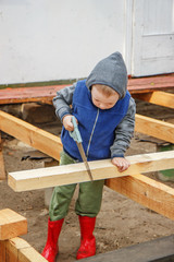 Little studious boy sawing a wooden board. Home construction. Li