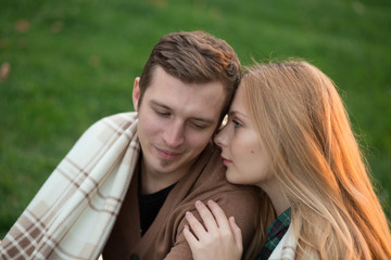 Fototapeta premium Tenderness of a young couple in the park. They are under covers.