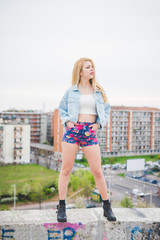 Obraz premium Young beautiful blonde caucasian girl posing on a small wall in