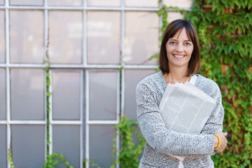 lächelnde frau mit tageszeitung