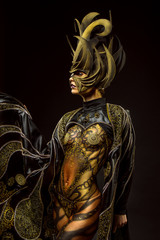 Studio portrait of beautiful model with fantasy golden butterfly body art and crown