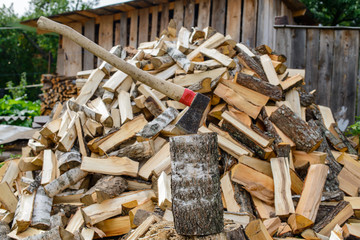 Closeup of an axe sticking in a chunk of firewood in front of a