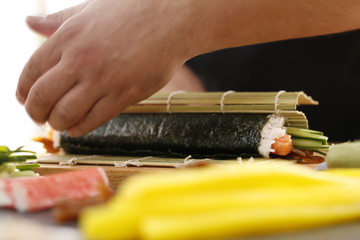 Sushi , etapy przygotowywania sushi z łososiem, paluszkiem krabowym, ogórkiem tykwą zawiniętego w glon nori