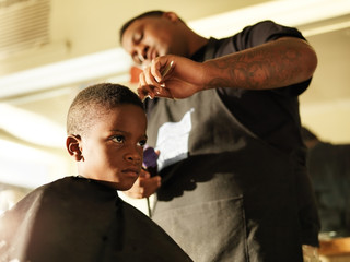 little boy getting his hair cut in barber shop