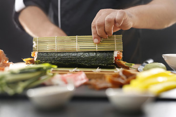 Sushi , etapy przygotowywania sushi z łososiem, paluszkiem krabowym, ogórkiem tykwą zawiniętego...