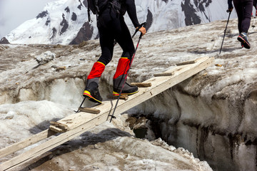 People Crossing Glacier Crevasse on Wood Shaky Footbridge Group of Mountain Climbers with High...