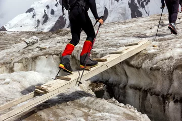 Papier Peint photo Lavable Alpinisme People Crossing Glacier Crevasse on Wood Shaky Footbridge Group of Mountain Climbers with High Altitude Boots and Clothing Crossing Ice Section During Ascent of Alpine Expedition in Asia Mountain Area