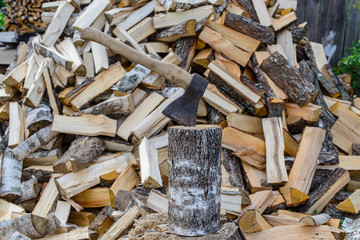 Closeup of an axe sticking in a chunk of firewood in front of a