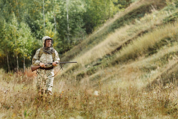 hunter in camouflage clothes ready to hunt with hunting rifle