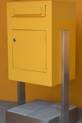 gelber Postkasten steht auf Betonsockel