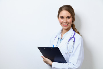 Friendly smiling young female doctor, standing near wall