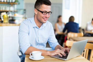 Fototapeta na wymiar Young man using laptop at cafe
