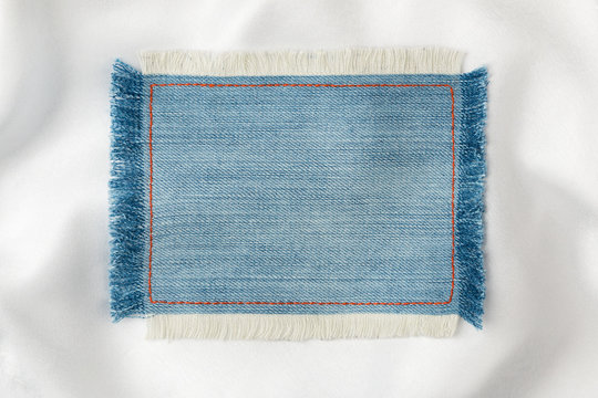 Frame made of denim fabric with yellow stitching on white silk