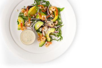 Salad with avocado and shrimp on the white ceramic plate