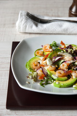 Salad with avocado , prawns and arugula on the  ceramic plate