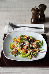 Salad with avocado and shrimp on the square ceramic plate  vertical