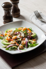 Salad with avocado and prawns on the ceramic plate with salt and pepper shaker