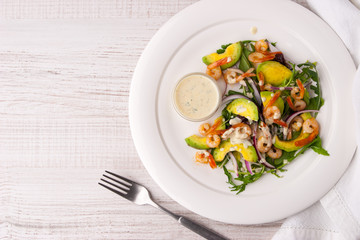 Prawns and avocado salad on the white plate with fork