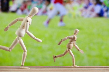 Art wooden models in running position, sport day in background