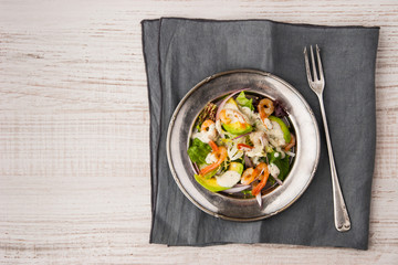 Salad with avocado and prawns on the old metal plate with vintage fork