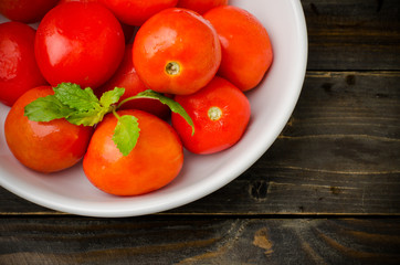Fresh tomatoes in the bowl on wooden background