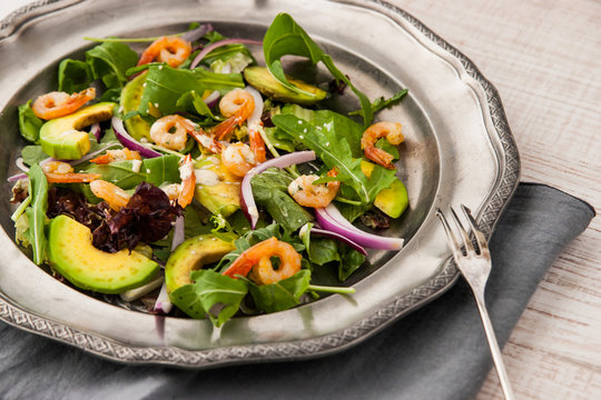 Prawns and avocado salad on the vintage metal plate with fork