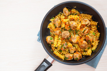 Fusilli pasta with sausage and vegetables in a frying pan