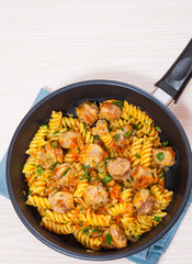 Fusilli pasta with sausage and vegetables in a frying pan