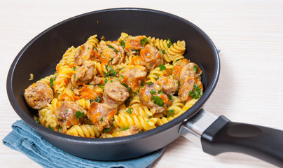 Fusilli pasta with sausage and vegetables in a frying pan