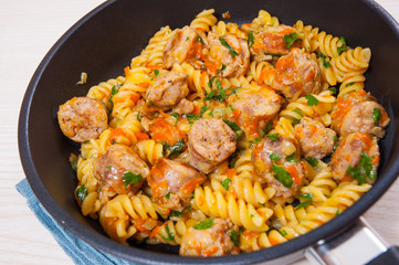Fusilli pasta with sausage and vegetables in a frying pan