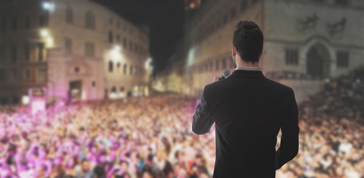 Uomo parla con microfono su palco 