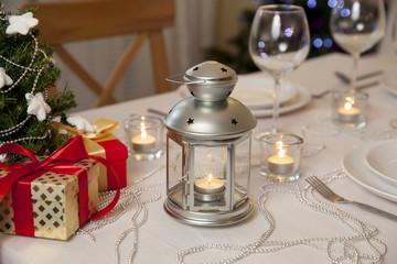 Fototapeta na wymiar Beautiful christmas table served and decorated with candles. Christmas tree with lights on the background
