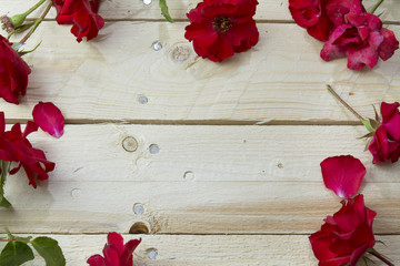 Frame of red roses on wooden background