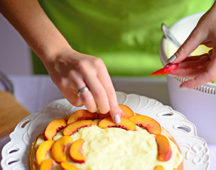 Woman hand put peach on the cake crust