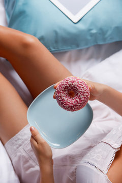 Woman eating a delicious donut in the bed
