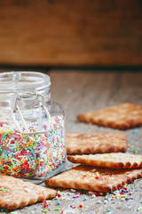 Sweet crackers with festive colored sugar balls on old wooden ba