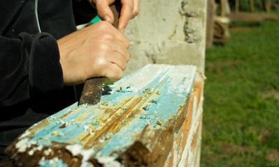 Close-up of woman's removing Paind from piece of Wood