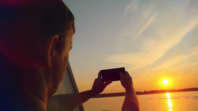 Man taking picture from his mobile phone of beautiful sunset