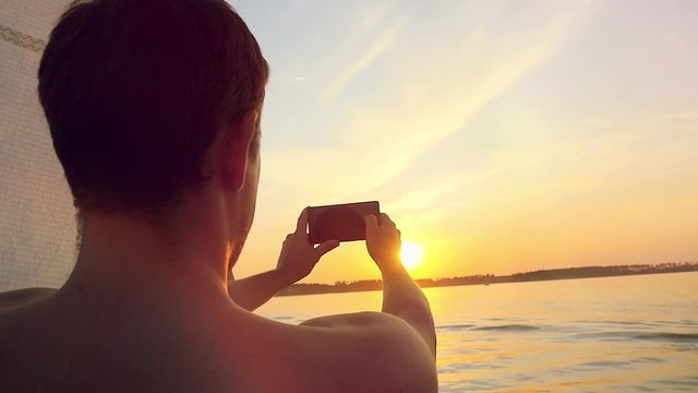 Man taking picture from his mobile phone of amazing sunset over